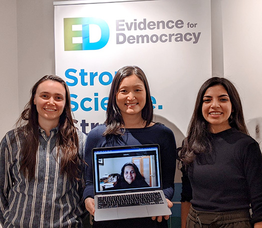 Three Evidence for Democracy team members in front of a roll-up banner